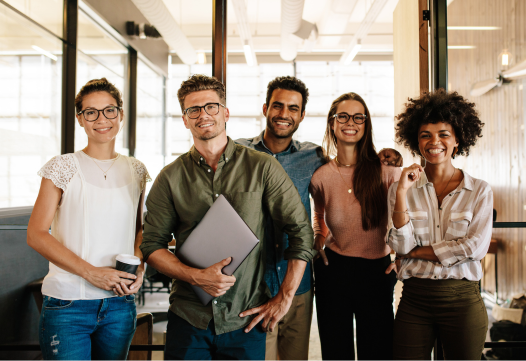 A group of happy young people at their jobs look at the camera