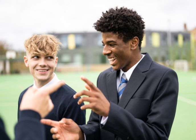 Two young people standing on a sports field smiling