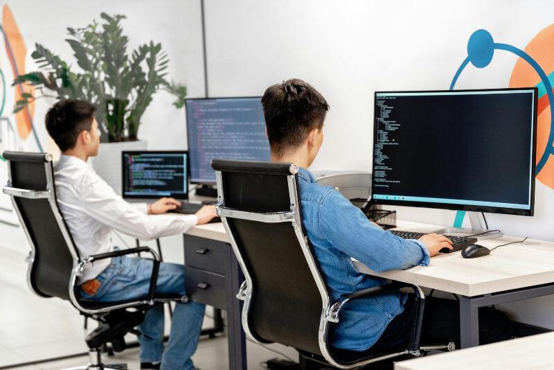 Two people using a computer Two young people are sat at their desks, using computers.
