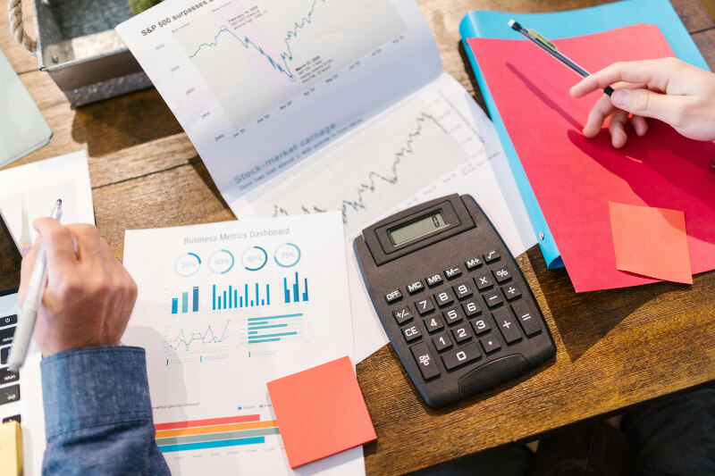 desk that is full of paperwork and a calculator, which arms are going over