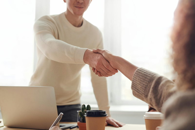 misconceptions2 a man standing up behind a desk shaking the hand of a woman sitting
