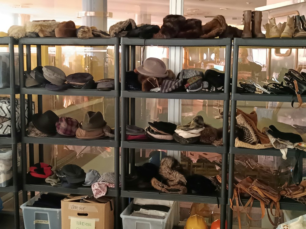 A rack of props for TV or movies. Most items on display are hats or boots, in an old fashioned style.