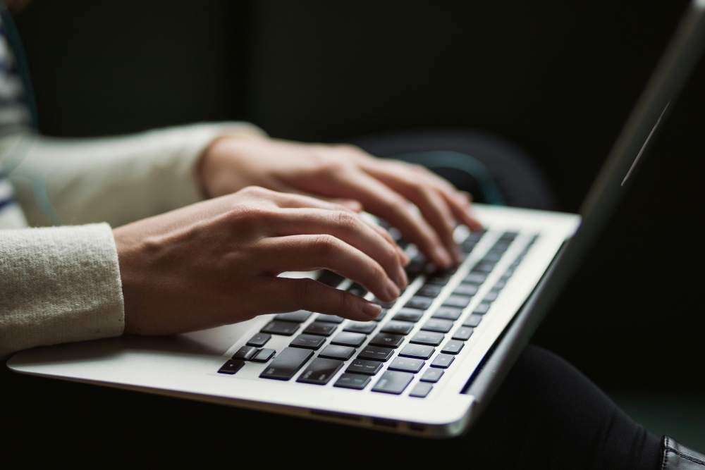 Close up image of a pair of hands on a laptop keyboard.