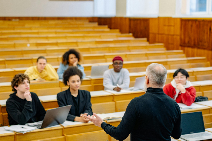 a group of people seated listening to a man standing in a lecture room