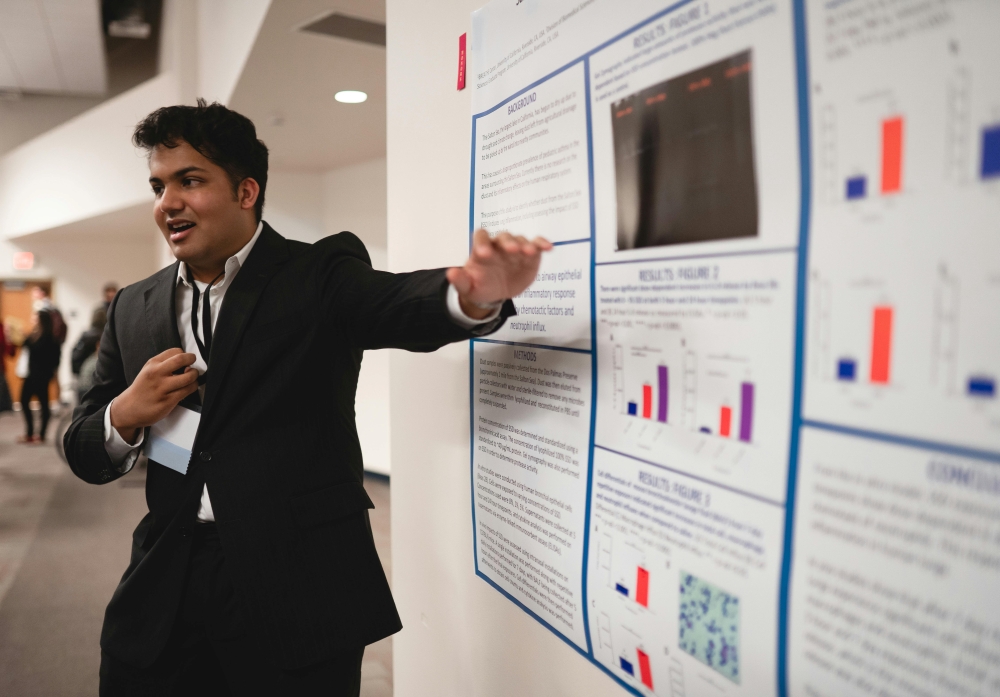 A young man in a suit pointing at information on a bulletin board