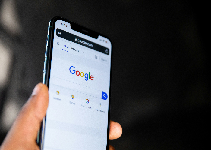a hand holding a phone displaying google