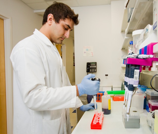 a man in a white lab coat handling equipment