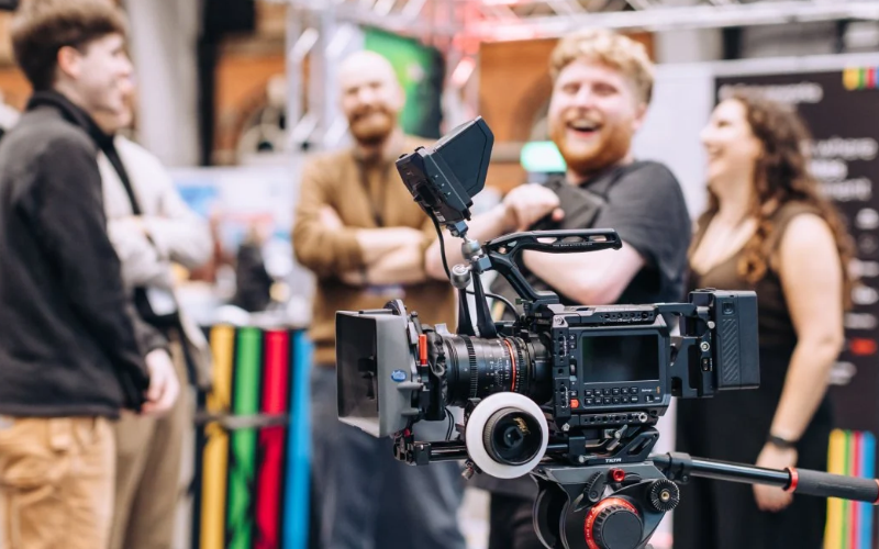 young people standing around a camera smiling